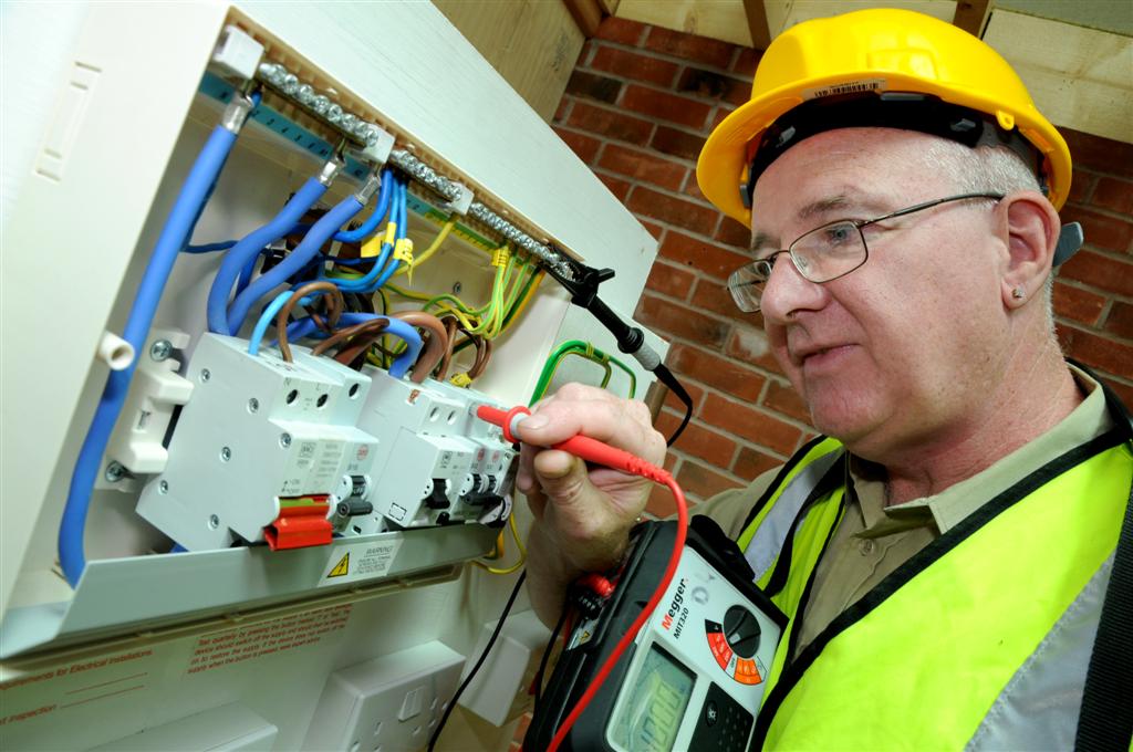 Photograph of a person wearing PPE working on an electrical panel