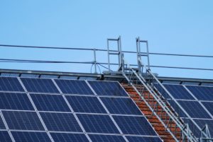 Photograph of solar panels fitted to a roof with scaffolding and ladders used to install in situ.