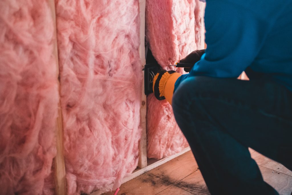 Photograph of a person installing wall insulation